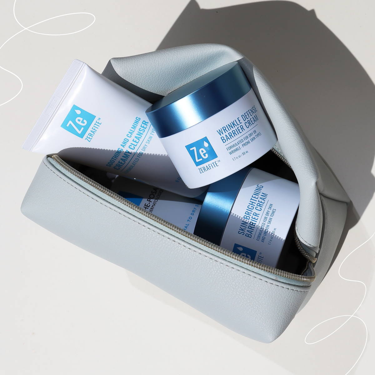 Zerafite skincare products including a jar and tube in a light blue pouch on a neutral background