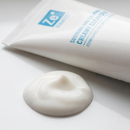 A dollop of white Zerafite Soothing and Calming Creamy Cleanser beside the tube.