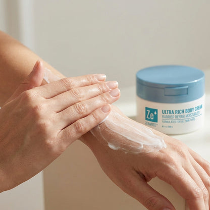 Two hands smoothing Zerafite Ultra Rich Body Cream along a forearm, the open tub behind.