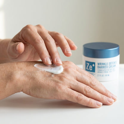 Two hands smoothing Zerafite Wrinkle Defense Barrier Cream into the back of one hand, the jar alongside.