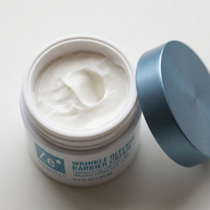 Open jar of Zerafite Wrinkle Defense Barrier Cream, lid beside it, showing white cream inside.