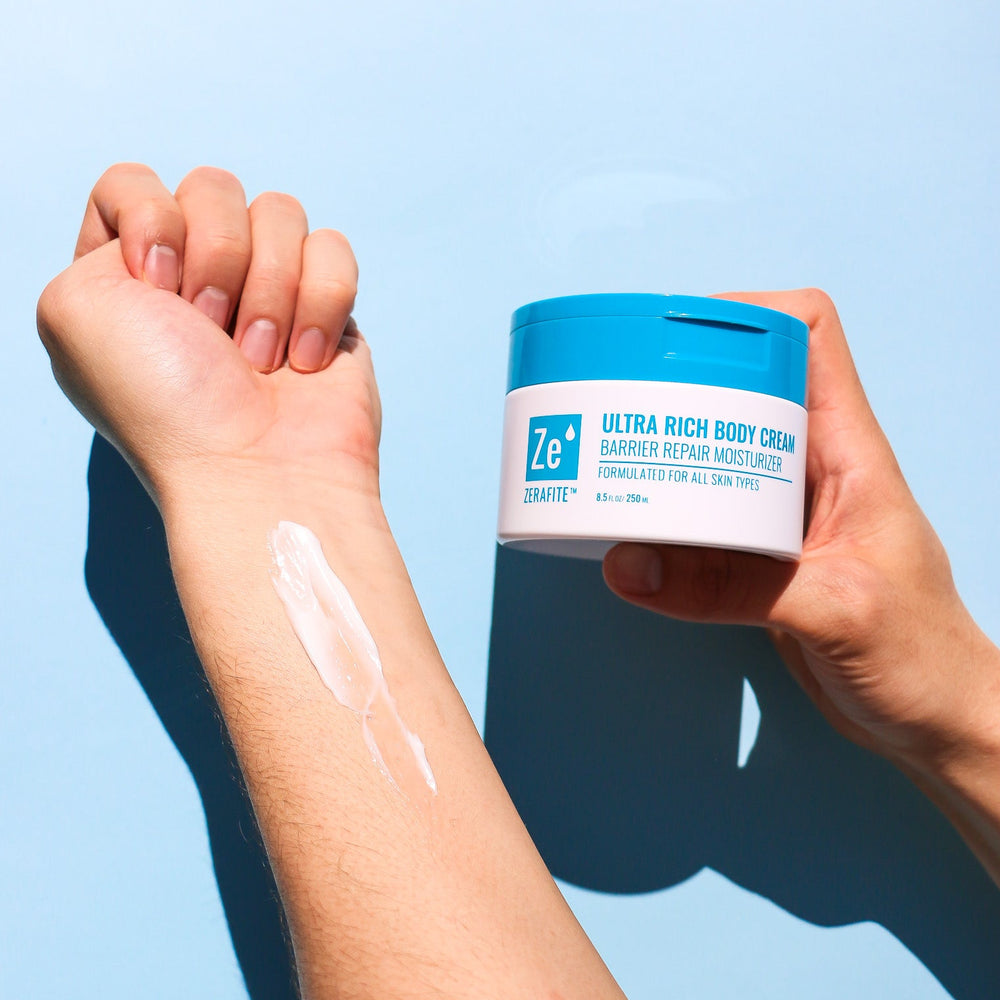 Person applying Ultra Rich Body Cream to their arm with a blue background
