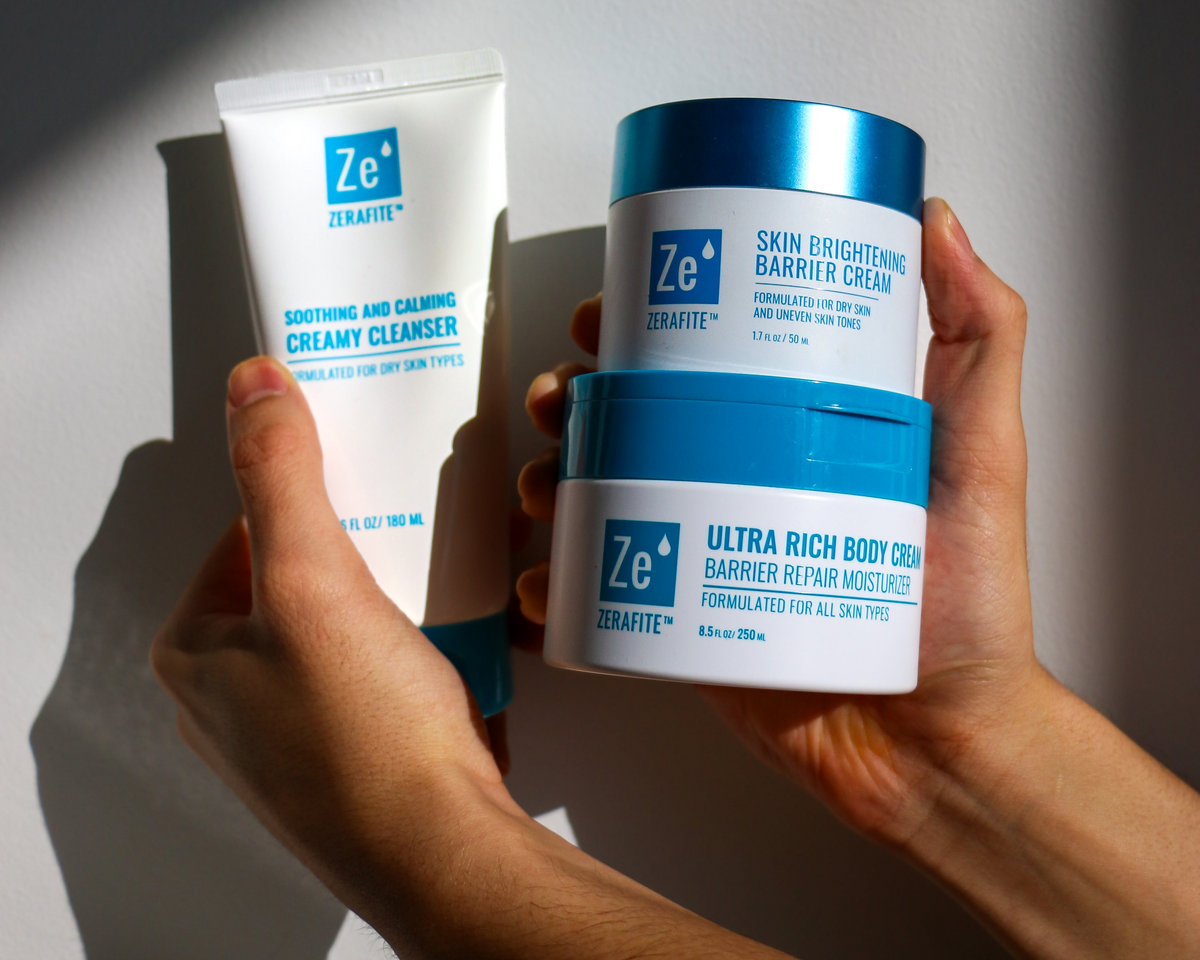 Hands holding Zerafite skincare products against a neutral background